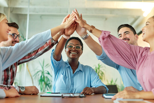 A portrait of young businesspeople celebrating with high five in the office