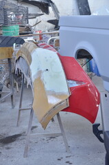 Professional auto body shop prepares car bumpers for repair and custom painting, showcasing meticulous craftsmanship for vehicle restoration projects.