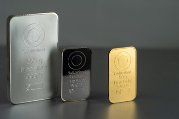 Gold and silver bars of various weights on a dark background.
Selective focus.