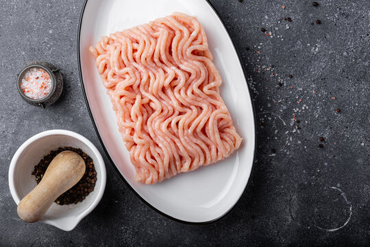 Raw chicken minced meat on cutting board and ingredients. Ground meat with ingredients for cooking on dark background. Top view