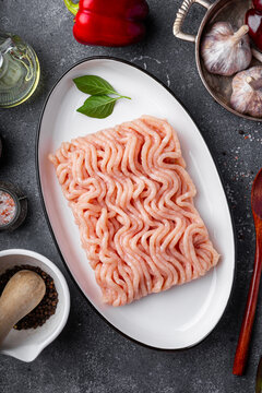 Raw chicken minced meat on cutting board and ingredients. Ground meat with ingredients for cooking on grey background. Top view