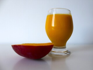 Ayurvedic cold drink garnished with a healthy, organic mango slice. With a white background and copy space.