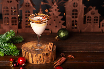 Elegant glass of Holiday eggnog cocktail with dark rum and milk garnished with nutmeg on dark Christmas background, copy space for text