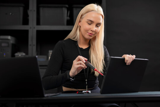 Young blonde IT technician repairing a laptop in a server room during maintenance and diagnostics
