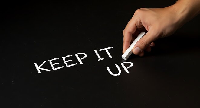 Hand writing keep it up message on a black surface with white chalk