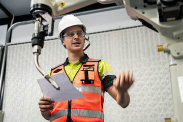 Fototapeta premium Technician checking robotic equipment with safety gear and paper sheet, symbolizing STEM training, AI technology, and industrial education. study project, repair and maintenance system