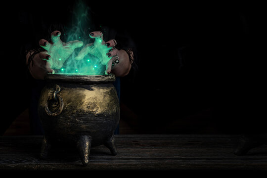 Witch's hands over a cauldron with a magic potion in a dark room. Witch casting spells on Halloween night