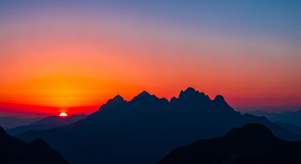 Obraz premium Stunning mountain range silhouetted against a vibrant sunset sky, painting the horizon with fiery oranges and soft purples, evoking peace and wonder.