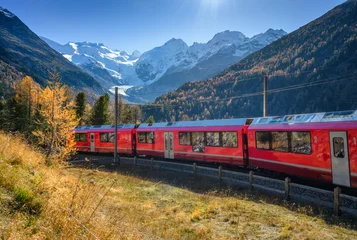 Gardinen Gletscher Red Bernina Express train passing through colorful autumn forest near Morteratsch glacier in the Swiss Alps, blue sky, golden trees and snowy mountain peaks in the background. Switzerland. Red train  © den-belitsky