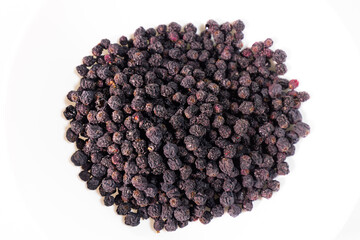 Detailed macro view of a dense, wrinkled, dark, dried  berries pile showing texture and natural variations. White background.