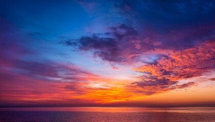 Obraz premium Colorful Sunset Sky With Vibrant Orange Pink Purple And Blue Hues Over Calm Horizon