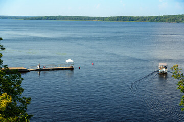 Small pier and boat on calm river with forested shoreline