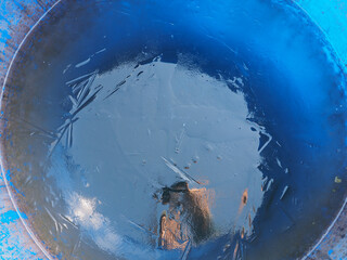 Close-up of a blue barrel with frozen water inside