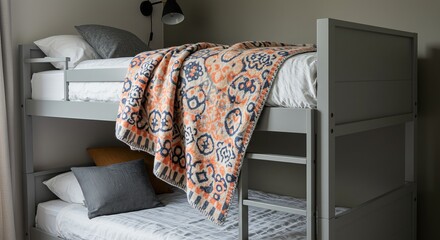 A gray metal bunk bed is shown with orange and blue patterned blankets and pillows on the beds.