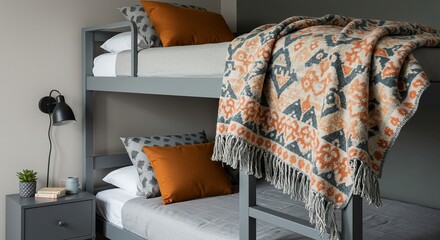 A grey bunk bed setup featuring cozy bedding, patterned throw pillows, and a vibrant patterned blanket draped over the top bunk.