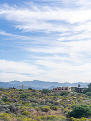 Fototapeta premium A scenic view of an rv and a building nestled in a landscape with mountains and a cloudy blue sky above