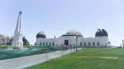 View of the griffith observatory with the hollywood sign in the background on a bright sunny day