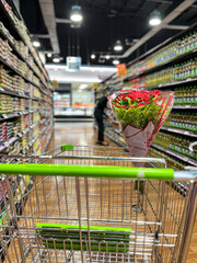 Shopping cart with bouquet of flowers in supermarket aisle