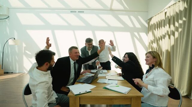 Business team celebrating success giving high fives in office