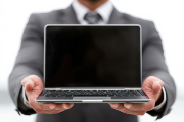A person in a suit holding a laptop with a blank screen, ready for presentation.