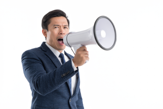 Asian businessman in a suit shouting into a white megaphone against a white background.