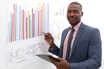 A man in a suit points to a colorful bar graph on a whiteboard, holding a tablet.