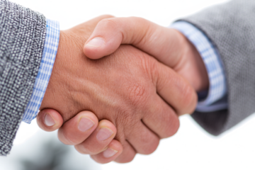 Two individuals in business attire engage in a firm handshake, symbolizing agreement, partnership, and successful negotiation.