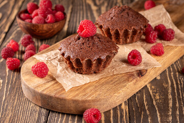 Gourmet chocolate muffins topped with fresh raspberries for a tasty delight