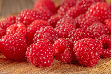 Close-up of fresh ripe raspberries scattered on a rustic table surface