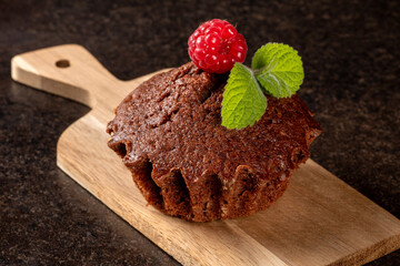 Close-up of a decorated raspberry muffin on a wooden cutting board