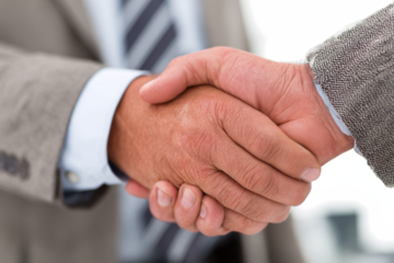Close-up of two businessmen in suits shaking hands, symbolizing agreement, partnership, or a successful deal.