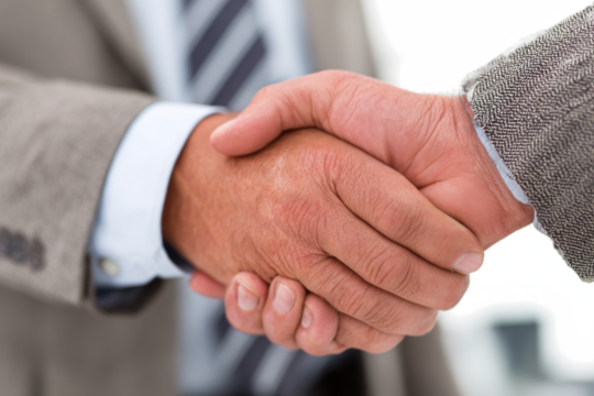 Close-up of two businessmen in suits shaking hands, symbolizing agreement, partnership, or a successful deal.