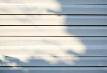 Fototapeta premium Subtle shadows play across light gray metal siding, highlighting texture, light, background
