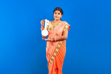 Indian woman in saree holding home key cutout on blue background