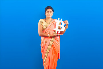 Modern Indian Female in Sari Displaying Bitcoin Sign Over Blue Backdrop