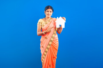 smiling indian housewife in traditional saree pointing finger towards home symbol