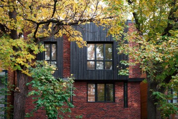 Modern brick building surrounded by autumn foliage, showcasing a blend of textures and colors in an urban setting during the fall season