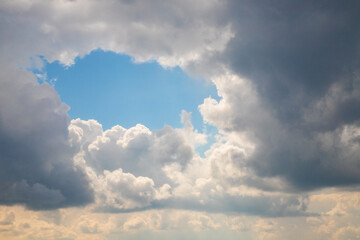 Dramatic sky with rain dark clouds and bright blue opening, nature's contrasting beauty