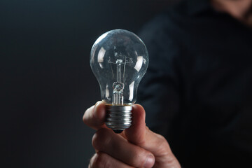 hand holding a light bulb on dark background. idea concept