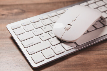 computer mouse on the keyboard of a computer on a wooden background.