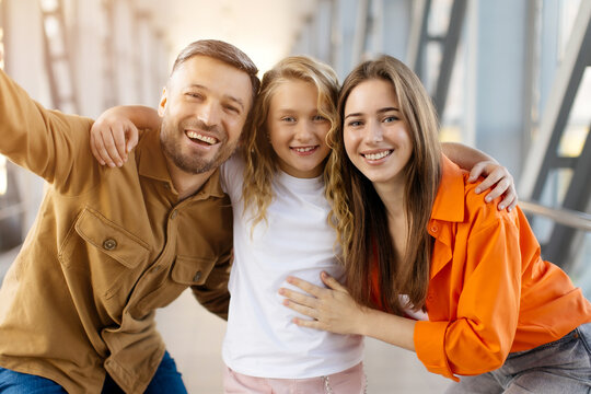 Smiling caucasian family with daughter taking selfie at airport, hugging together, symbolizing happy bonding, lifestyle, parenting and joyful travel experience - Powered by Adobe