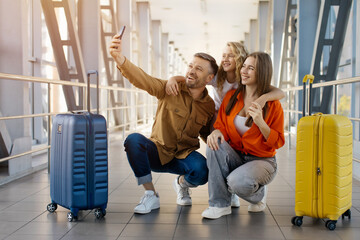 Caucasian family of three taking selfie at airport with luggage, smiling together and enjoying cheerful bonding, lifestyle, modern travel happiness and holiday departure