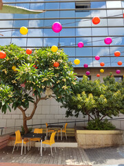 Haifa, Israel, 12 June 2025,  Vibrant Urban Patio with Floating Balloons and Glass Facade