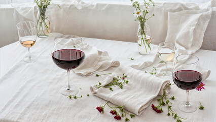 Red wine glass and flowers on white tablecloth