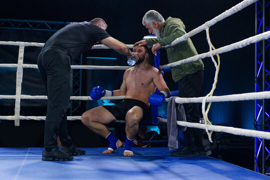 Cornered boxer receives strategic advice from trainer during intense bout.