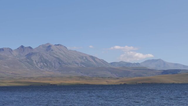 Majestic Mount Aragats rising above serene Lake Aparan, revealing pristine Armenian landscape with tranquil waters reflecting expansive highland scenery