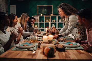 Woman serving thanksgiving turkey to friends at festive dinner table