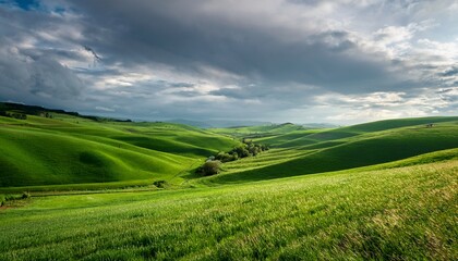Obraz premium Lush Green Fields And Rolling Hills Under A Cloudy Sky In A Rural Countryside Setting