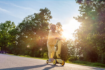 Girl on scooter. Riding child outdoor fun. Sunshine road freedom lifestyle.
