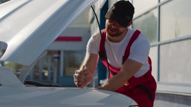 Mechanic in red overalls working on car engine with tools, focused on vehicle diagnostics, showcasing automotive repair skills and dedication to quality service